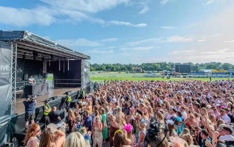 The crowd dancing to a live DJ set in the sunshine at Uttoxeter Races